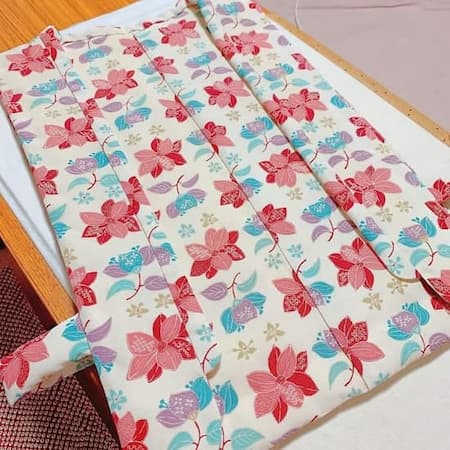 オフホワイト地に赤や青の花柄が描かれた防寒着