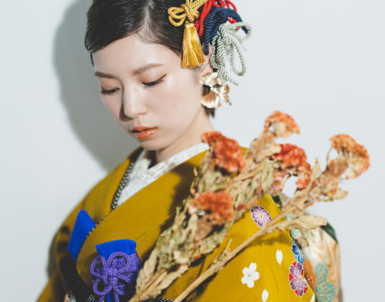 髪飾りをつけた女性が黄色い着物で花を持っている様子